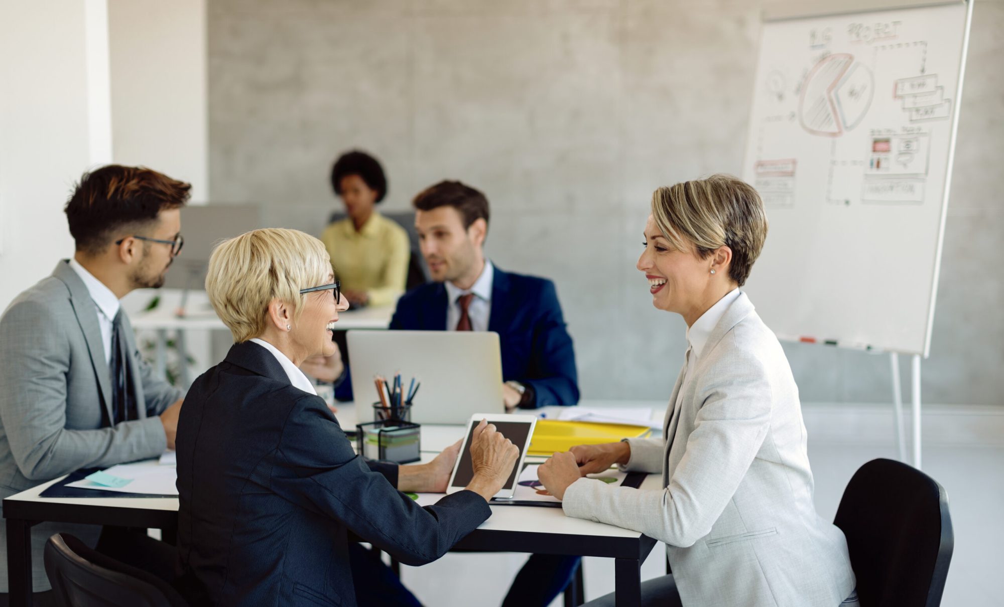 Happy mature businesswoman communicating with her younger colleague on a meeting in the office.